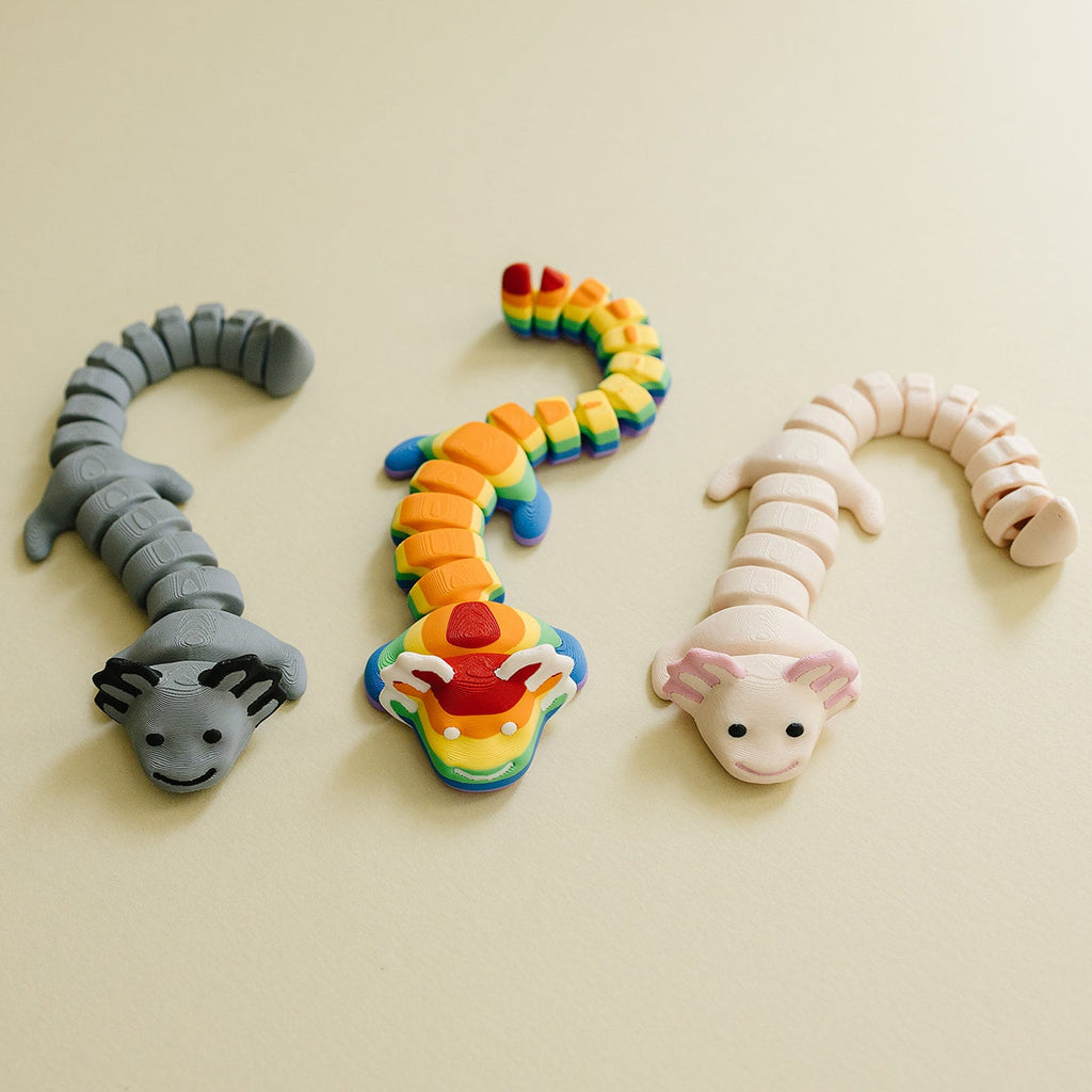 Three colorful axolotl fidgets on a beige background